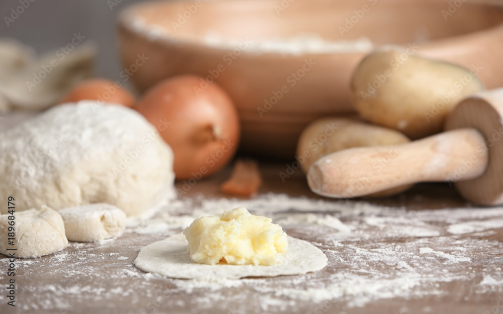 Fototapeta premium Raw dough with mashed potatoes for dumpling on wooden table
