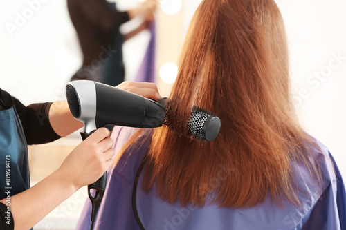 Professional hairdresser working with client in salon