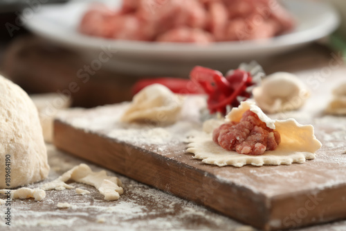 Raw dough with minced meat for dumpling on wooden board