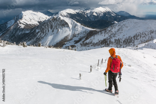 Mountaineer walking on the snowy slope of the Dovska Baba mountain in Karavanke range, Slovenia 