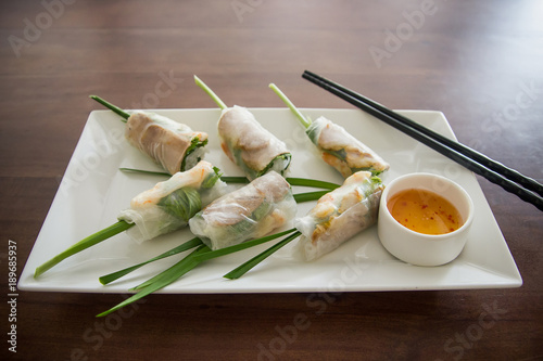 Fresh spring rolls Vietnamese lunch on wooden table. Asian food background.
