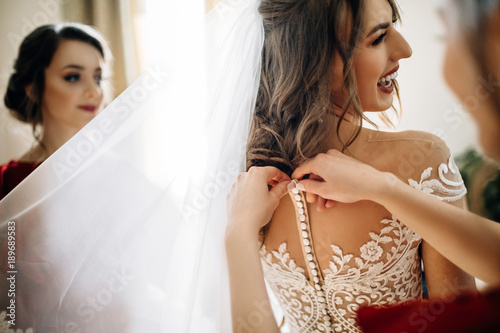 Bridesmaids help bride to get ready for a wedding