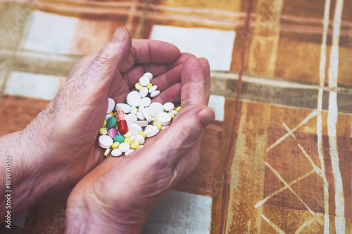 Senior woman holding out hands full of pills, close-up