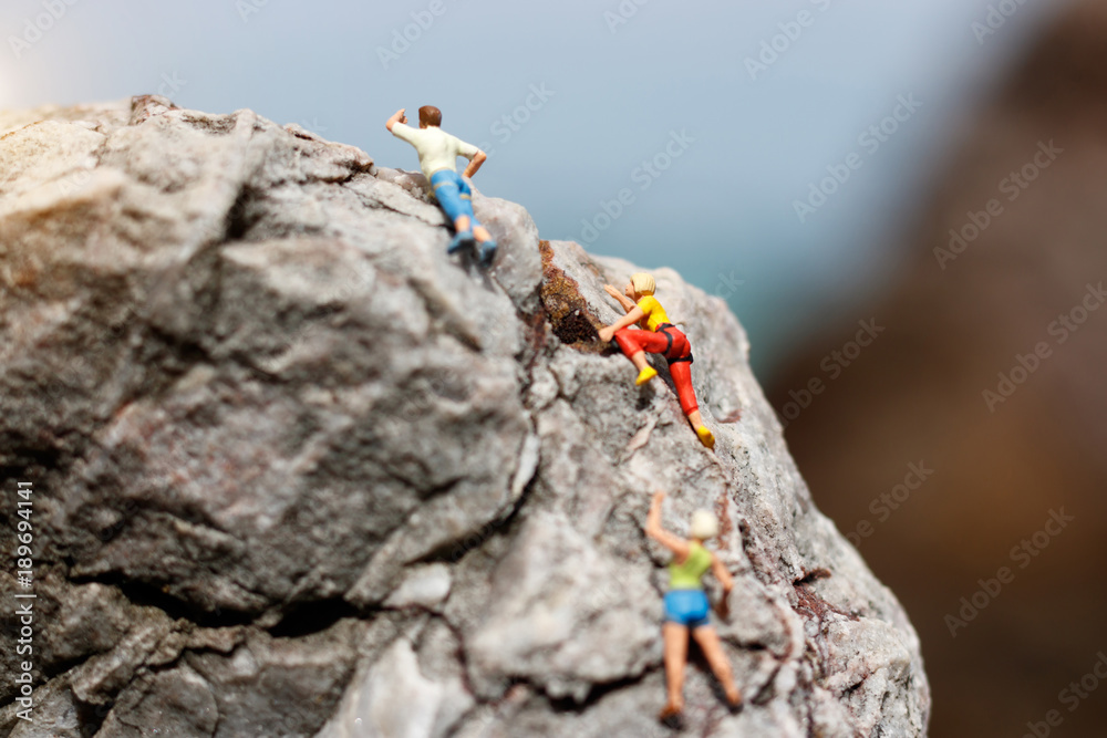 Obraz premium Miniature people: Climber looking up while climbing challenging route on cliff, Concept of the path to purpose and success.
