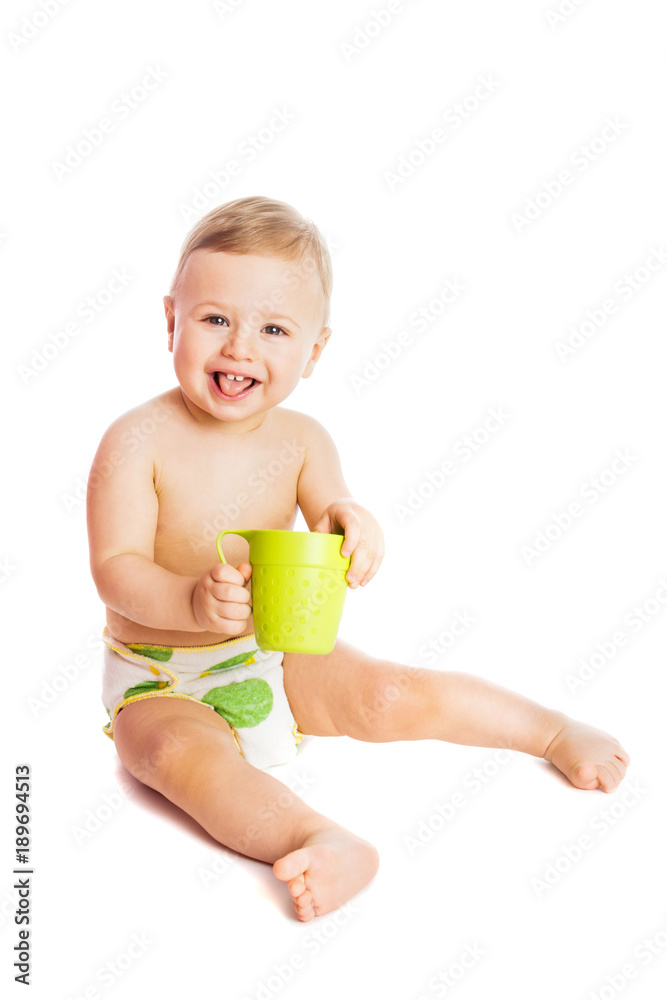 Cute baby in diaper holding a green cup smiling, sitting, isolated on white background Cute baby in diaper holding a green cup smiling, sitting, isolated on white background