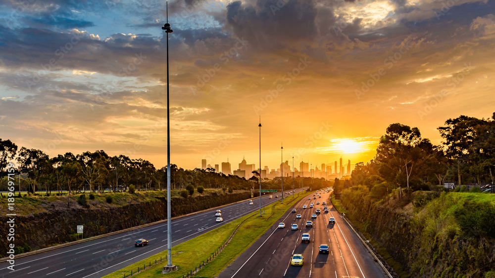 Obraz premium Widok wzdłuż wschodniej autostrady w kierunku miasta Melbourne w Australii podczas zachodu słońca.