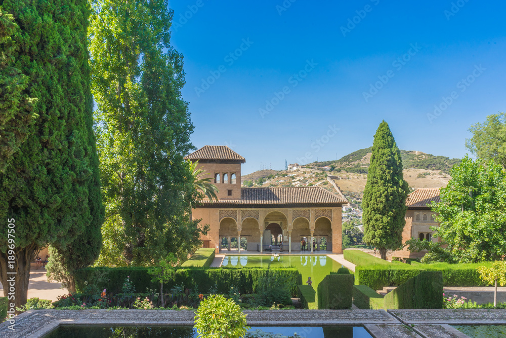 Obraz premium El Partal. A large central pond faces the arched portico behind which stands the Tower of the Ladies, inside the Alhambra of Granada, Andalusia, Spain, Europe