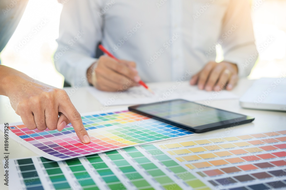 Graphic design partners working together renovation and technology concept - on a desktop computer and selection using some color swatches. Graphic design partners working together renovation and technology concept - on a desktop computer and selection using some color swatches.