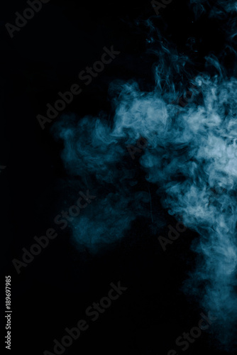 Steam texture from a hot drink on a black background. Blue smoke with copy space.
