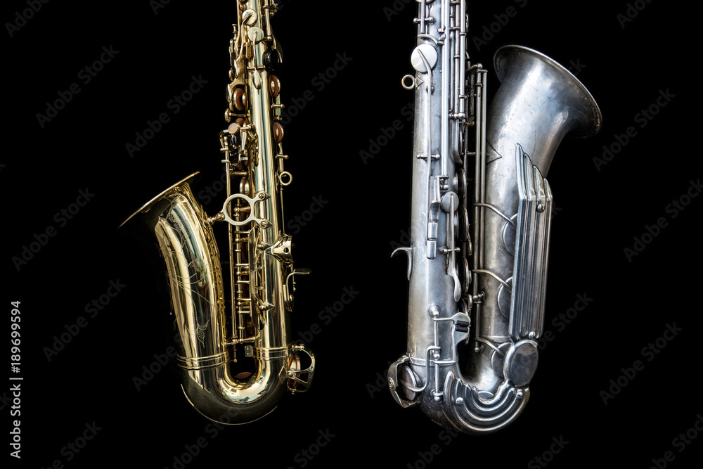 Obraz premium Close up of two saxophones standing isolated in black