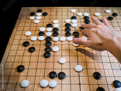 close up of player hand make a move in Go game Weiqi  Traditional asian strategy board game