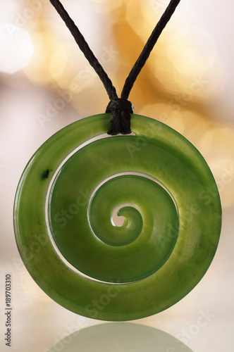 Grüne Jade Spirale als Symbol Schmuck Schmuckstein Anhänger Koru aus Neuseeland mit Bokeh Hintergrund. photo