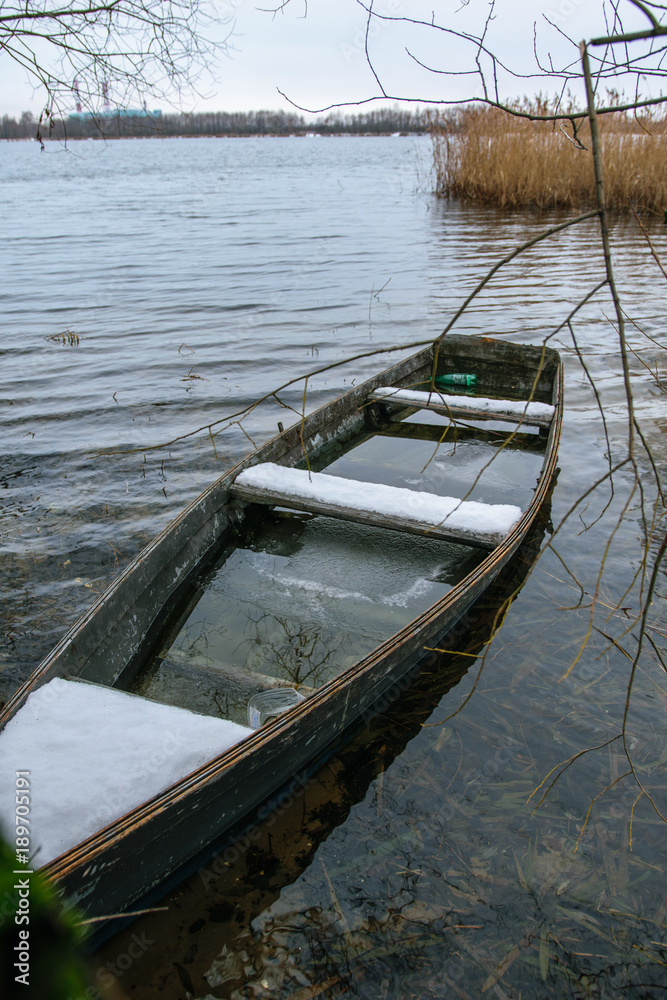 Obraz premium Sunken fishing boat on winter lake in Shatura in Moscow Region, Russia