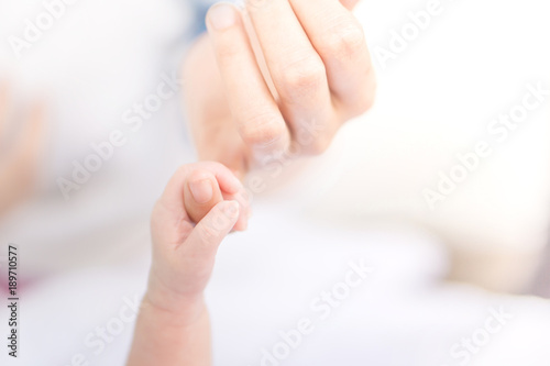 new born little hand holding mum finger in soft tone background with copy space