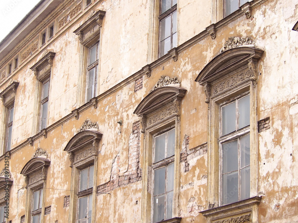 An old uninhabited tenement house in the old town of Krakow. Beautiful windows and destroyed façade.