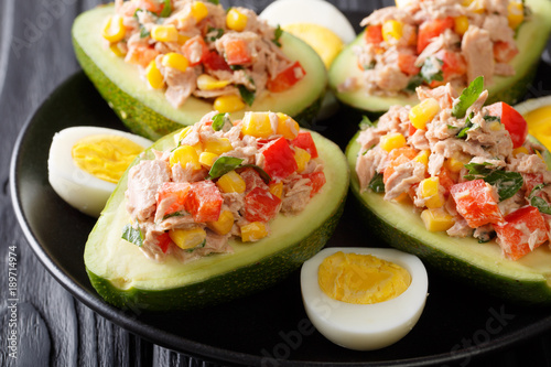 Ripe avocado with a salad of tuna and vegetables close-up on a plate. horizontal