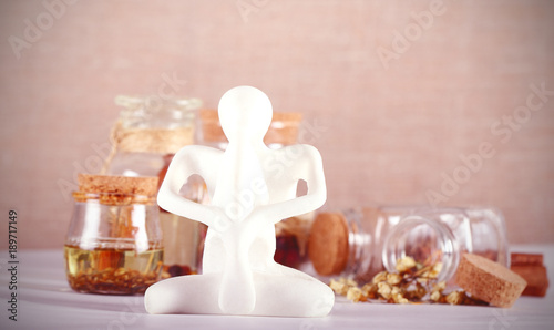 фигурка йога стоит на столе рядом баночки с маслами 