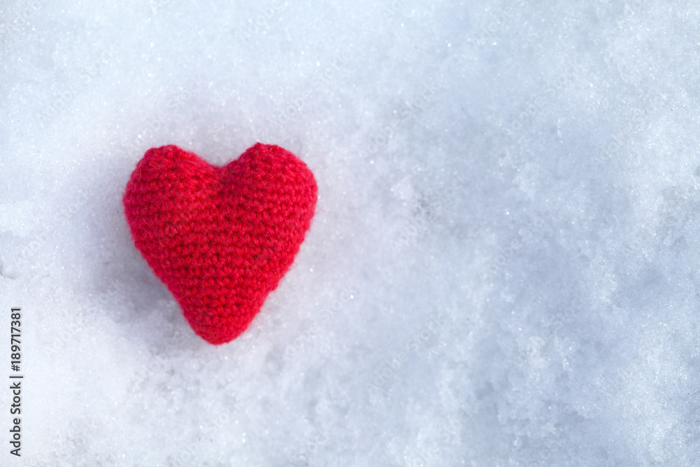 The heart is tied with red woolen threads and lies on white snow. Template for a greeting card for the feast of Saint Valenotine.