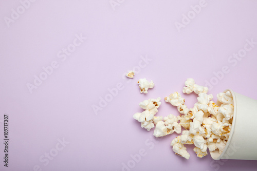 Spilled popcorn from a paper cup on a pink background, empty space for text. © Andrii Zastrozhnov