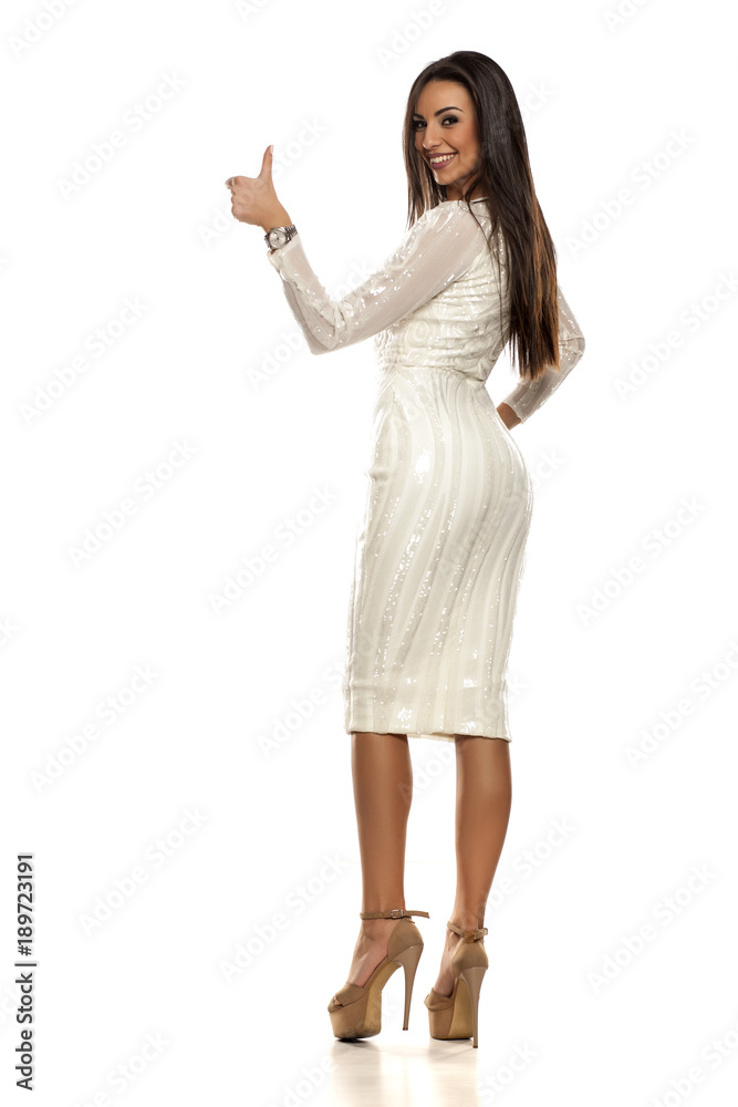 young beautiful woman in a white dress showing thumbs up on a white background young beautiful woman in a white dress showing thumbs up on a white background