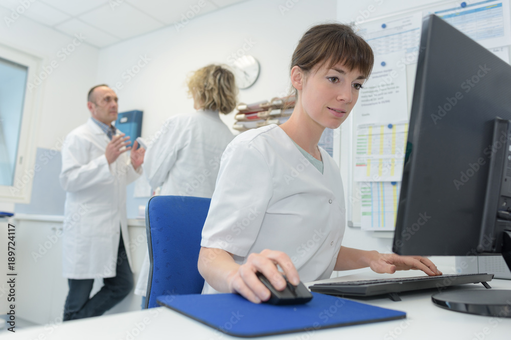 Obraz premium happy female doctor at the computer in hospital room