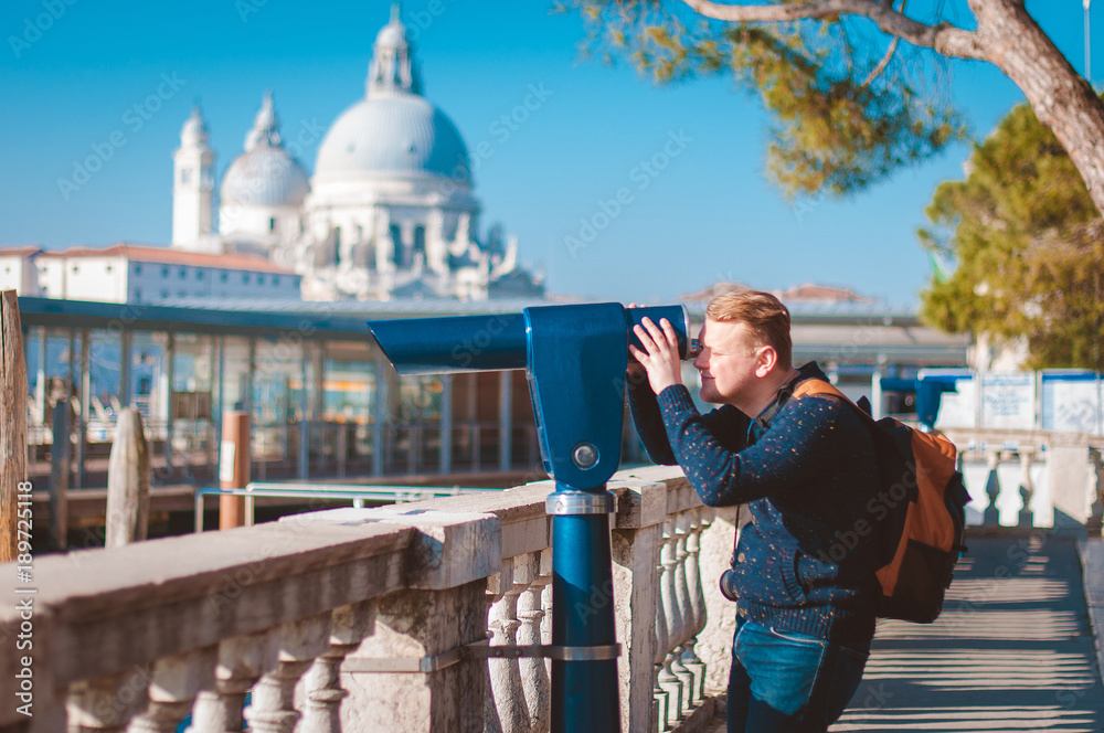 A tourist's husband looks at the telescope in Venice, Italy