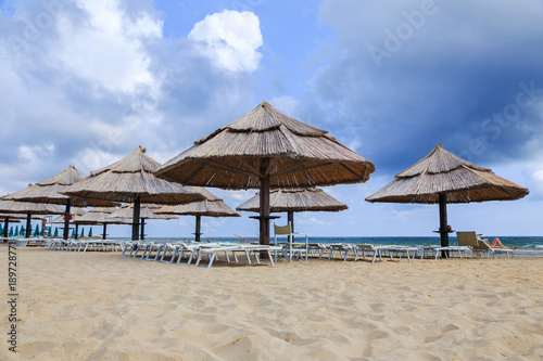 Straw umbrellas on a beautiful tropical beach background. © simone_n