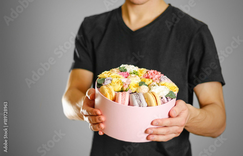 Man holding flowers and cookies in a box. Hands holding rocket in a hatbox © OB production
