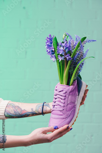 cropped image of girl holding shoe with hyacinth flowers