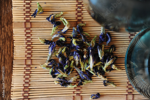 The flowers of Thai blue tea Anchan are scattered on a bamboo mat close-up