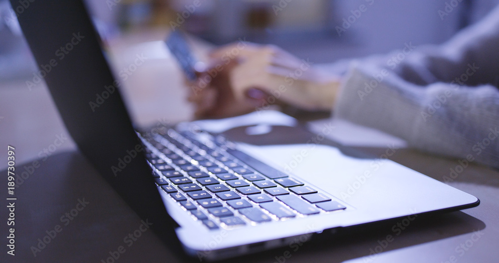 Shopping online on laptop computer at home in the evening, paying credit card bill Shopping online on laptop computer at home in the evening, paying credit card bill