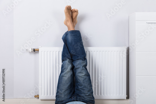 Man Warming Up His Feet On White Radiator