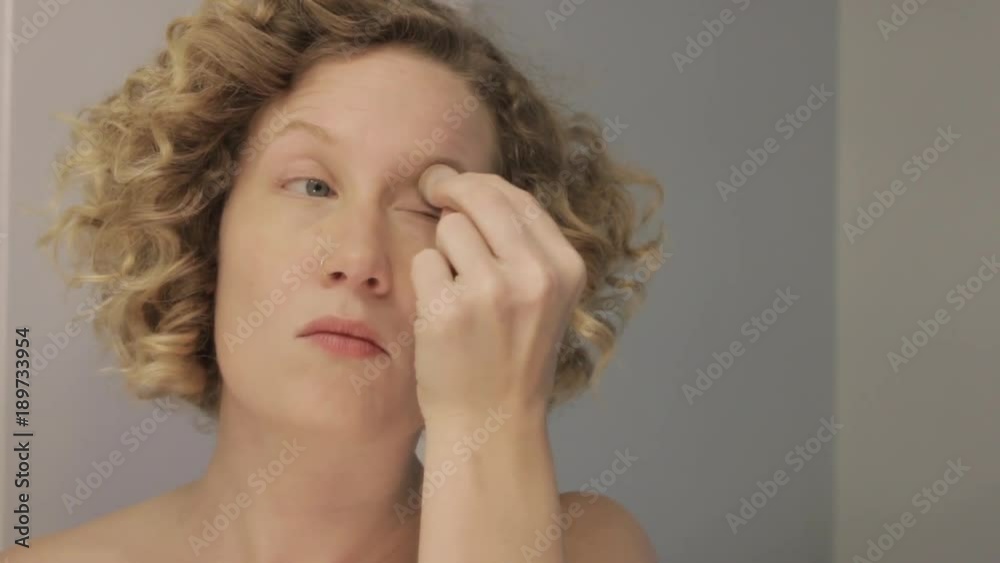 Young woman applying makeup. Getting ready for the day. Young woman concealing under-eye circles. Left-handed. Young woman applying makeup. Getting ready for the day. Young woman concealing under-eye circles. Left-handed.