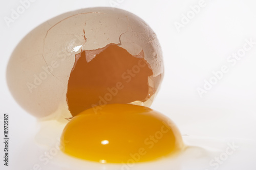Rozbite jajko - białko i żółtko wypłynęło poza skorupkę, widoczne wnętrze skorupki