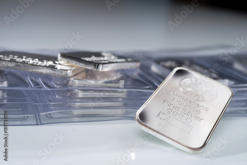 Silver ingot weighing one troy ounce against the backdrop of many packaged bars.