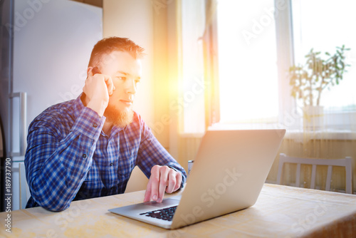 Young businessman looking at a chart that is lying on his laptop photo