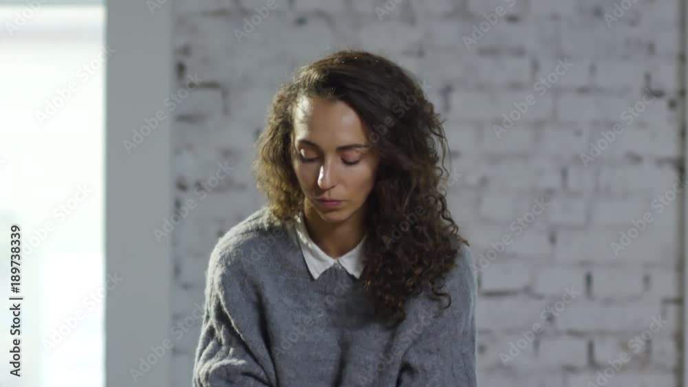 Medium shot of anxious young woman with curly hair explaining problem to unrecognizable male psychotherapist during appointment Medium shot of anxious young woman with curly hair explaining problem to unrecognizable male psychotherapist during appointment