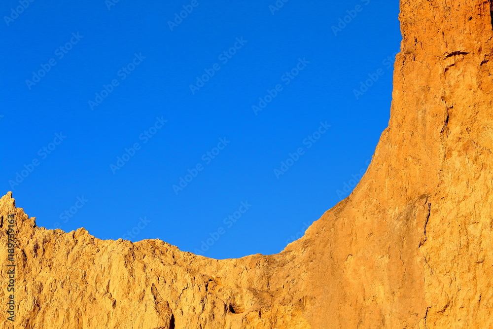 Fragment of clay orange cliff and blue sky