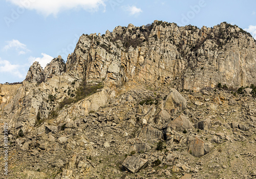 inaccessible high mountain with stony slope against the blue sky with clouds, extreme walk