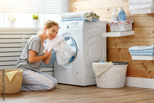 Happy housewife woman in laundry room with washing machine