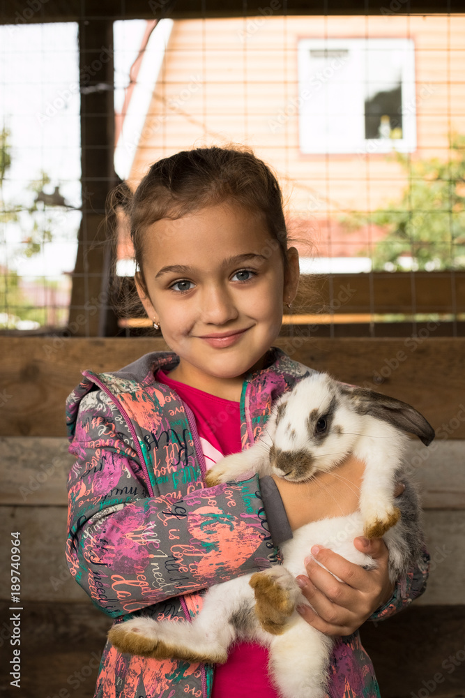 Rabbit. Happy Little Girl With Cute Rabbit In Her Embrace. Girl Playing With White, Grey Rabbit Indoor. Children Feeding Animal. Family With Animals.