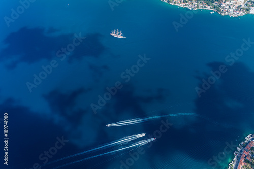 Aerial view of motor boats that run along the water surface leaving a white trail. Montenegro.