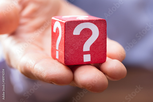 Person Showing Question Mark On The Red Wooden Block