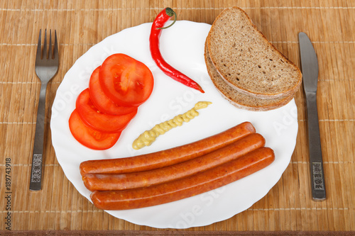 Breakfast - sausages, vegetables and bread on a white plate