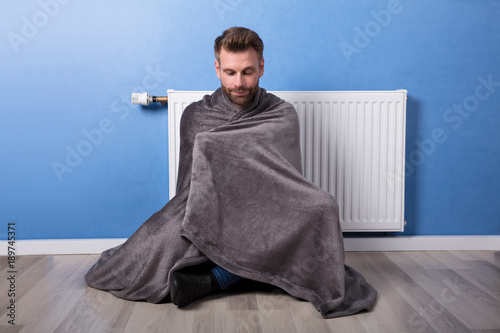 Man Sitting In Front Of Heater At Home