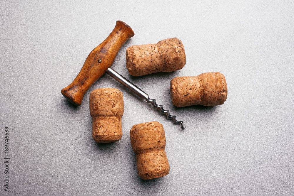 Vintage corkscrew and wine corks on a light gray background