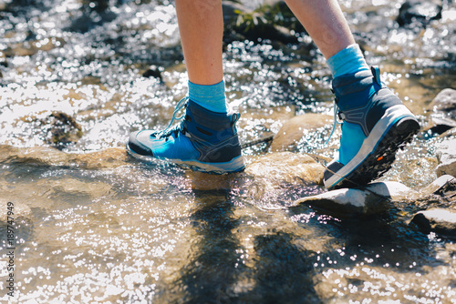 Hiking shoes - sole of trekking boots and legs in a mountain stream