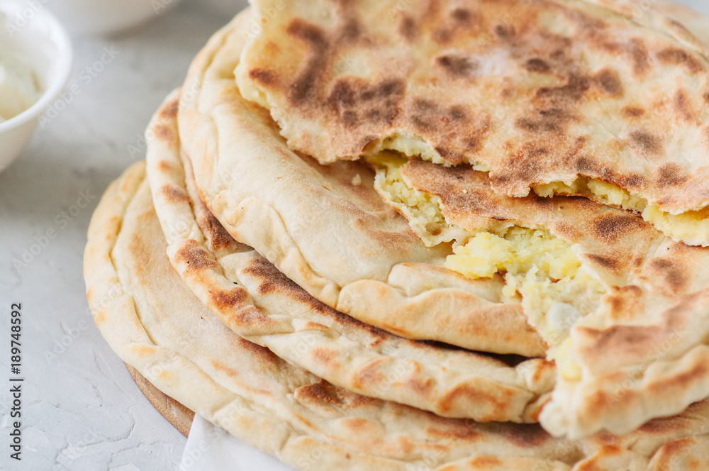 Mashed potato and sheep cheese filling flatbread on a white stone background. Mashed potato and sheep cheese filling flatbread on a white stone background.