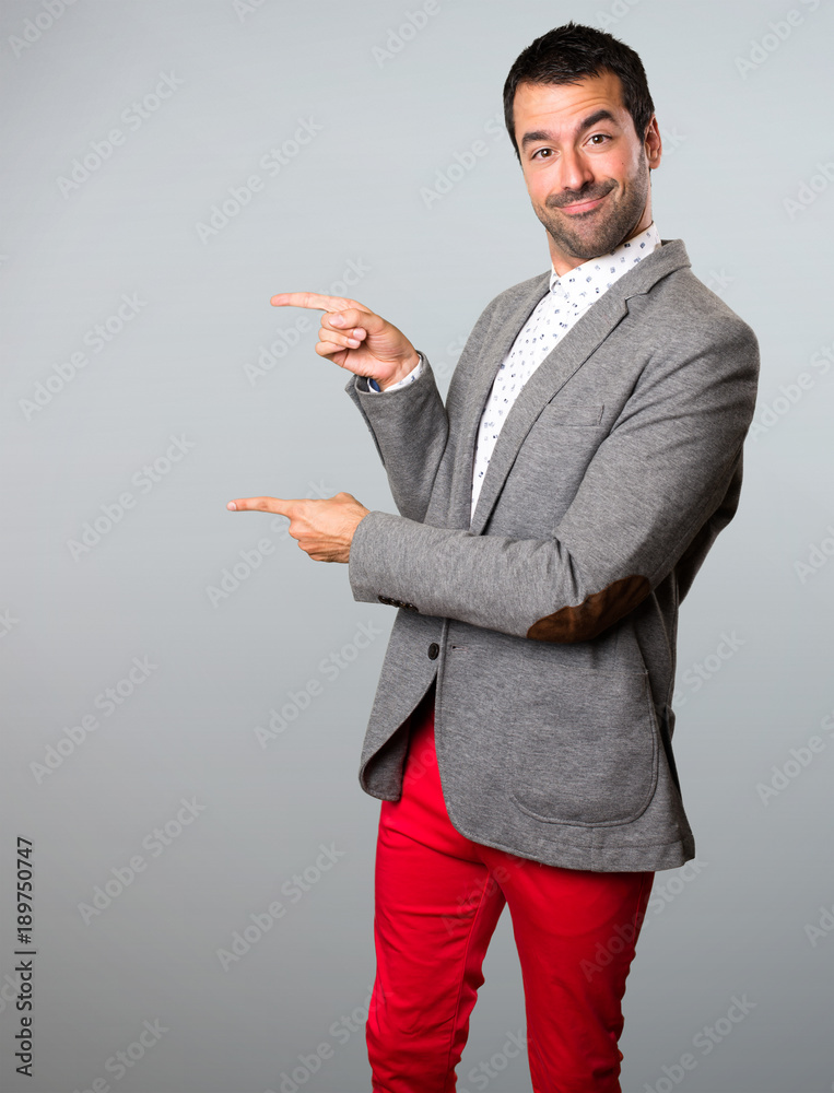 Handsome man pointing to the lateral on grey background Handsome man pointing to the lateral on grey background