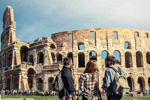 Photography Three young friends tourists standing in front of colosseum in rome with backpacks sunglasses happy beautiful girl long hair